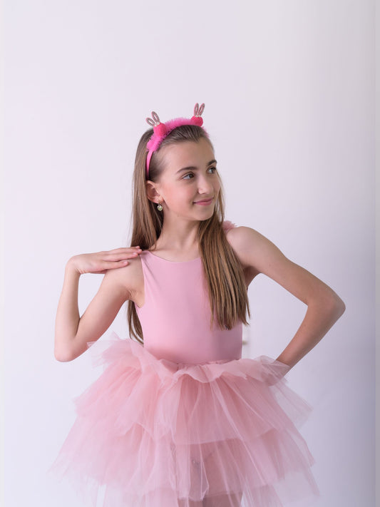 a little girl in a pink dress posing for a picture