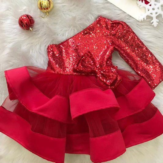 Front view of red Christmas girl dress with sequin design, one long shoulder, and puffy fluffy skirt for babies. Baby Girl Dress
