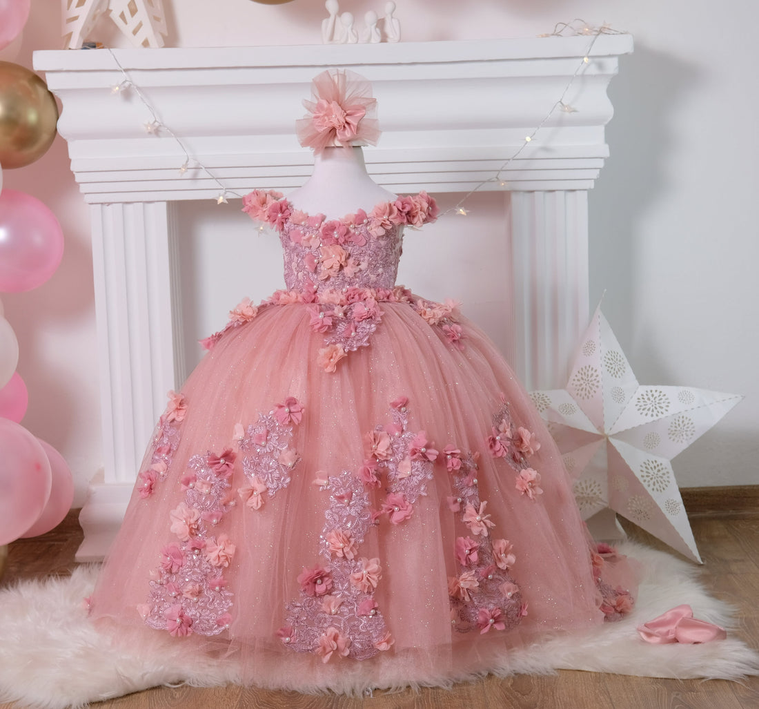 Blush pink Quinceañera gown featuring a satin bodice adorned with 3D colorful flowers and intricate lace details, with a soft cotton lining for comfort. The multi-layered tulle skirt includes glittery tulle, lace, and 3D flowers, complemented by a cotton lining. Comes with a matching gift hair accessory. Baby Girl Dress for Special Occasion