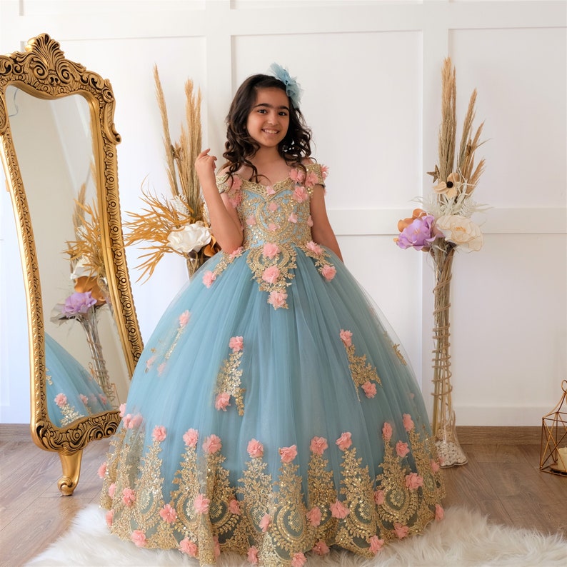 The bodice of the light pastel blue dress is laced and has laser flowers on it. The whole skirt is embroidered with lace and tulle on tulle. Baby Girl Dress for Special Occasion