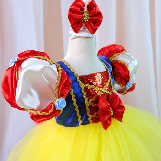 a little girl wearing a yellow and red dress
