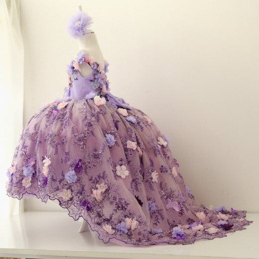 Lilac quinceañera dress featuring a satin bodice with intricate lace and 3D floral appliqués, a layered tulle skirt with glitter accents, and a matching hair accessory, perfect for a memorable celebration. Baby Girl Dress