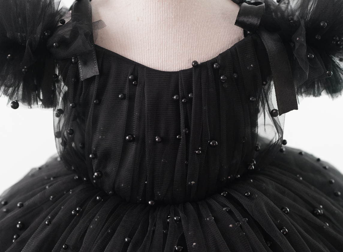 a woman wearing a black dress with pearls on it Baby Girl Dress