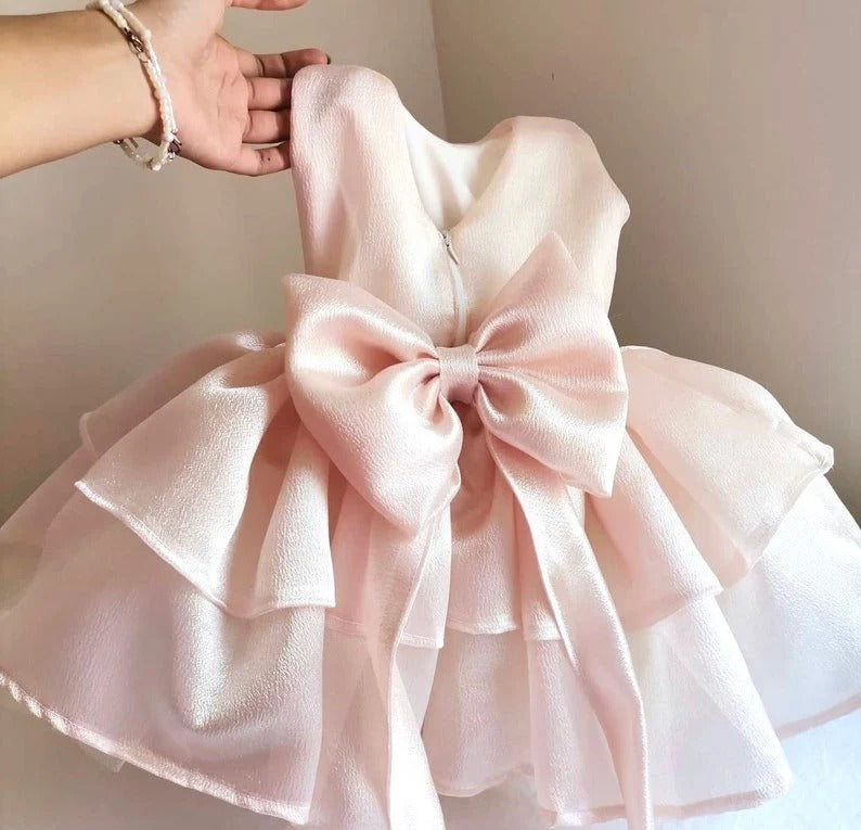 a hand holding a pink dress with a big bow Baby Girl Dress for Special Occasion