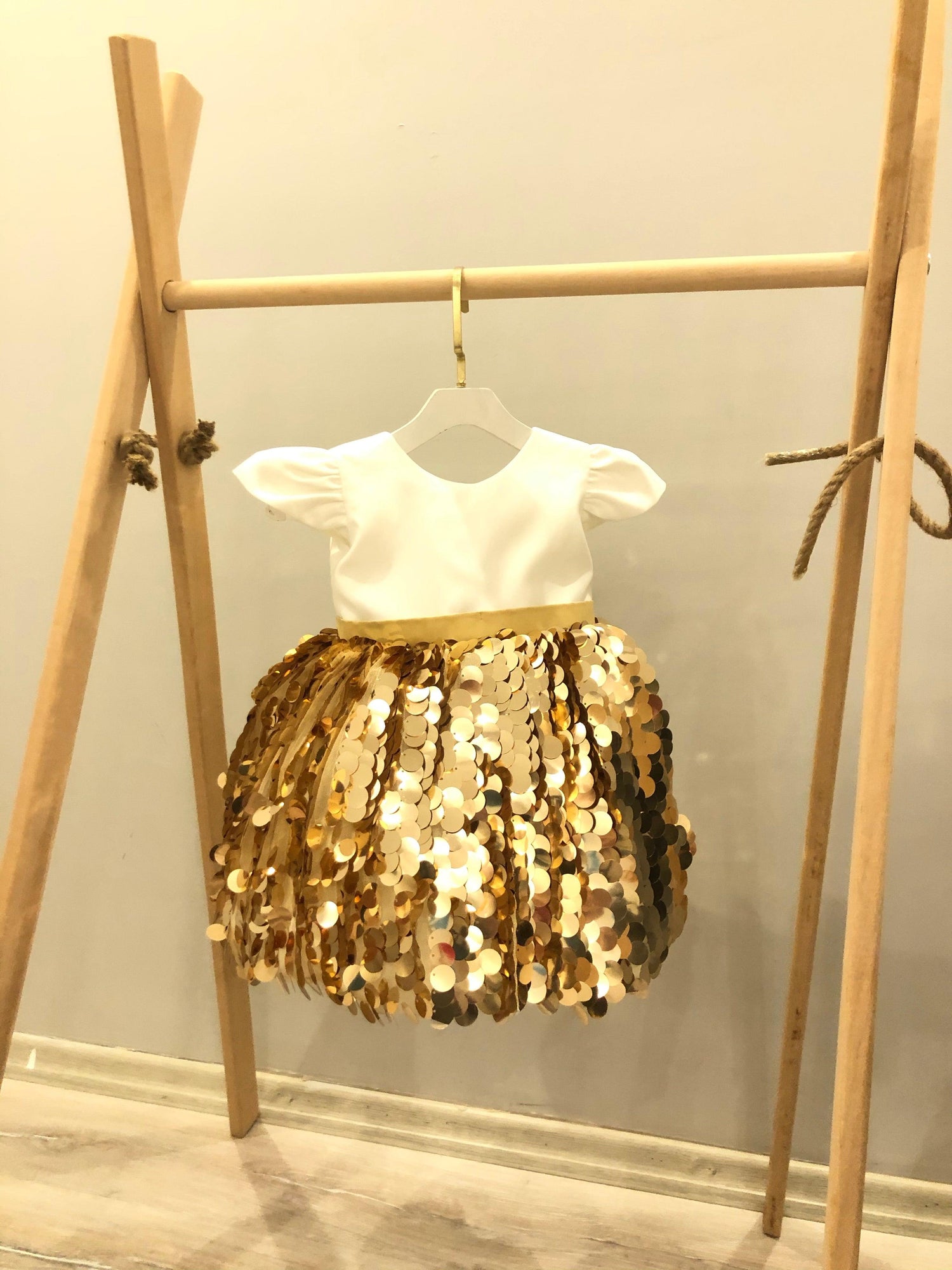 Girl’s gold dress featuring a smooth satin bodice and a glittering sequin skirt, perfect for parties and celebrations. Baby Girl Dress