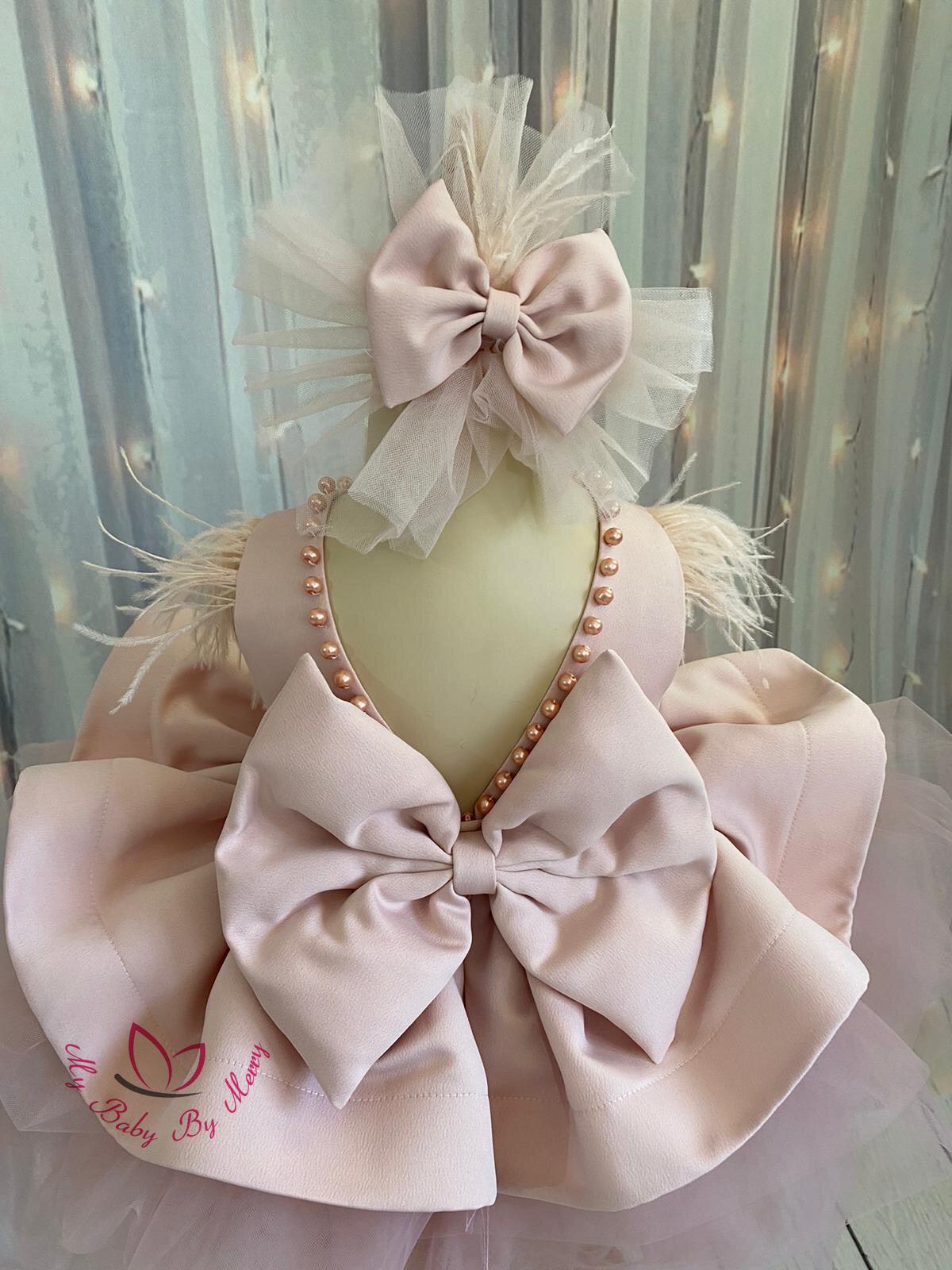 Adorable blush baby girl dress with delicate pearl detailing, featuring a soft and elegant design. Perfect for special occasions, this dress combines charm and comfort for your little one. Baby Girl Dress