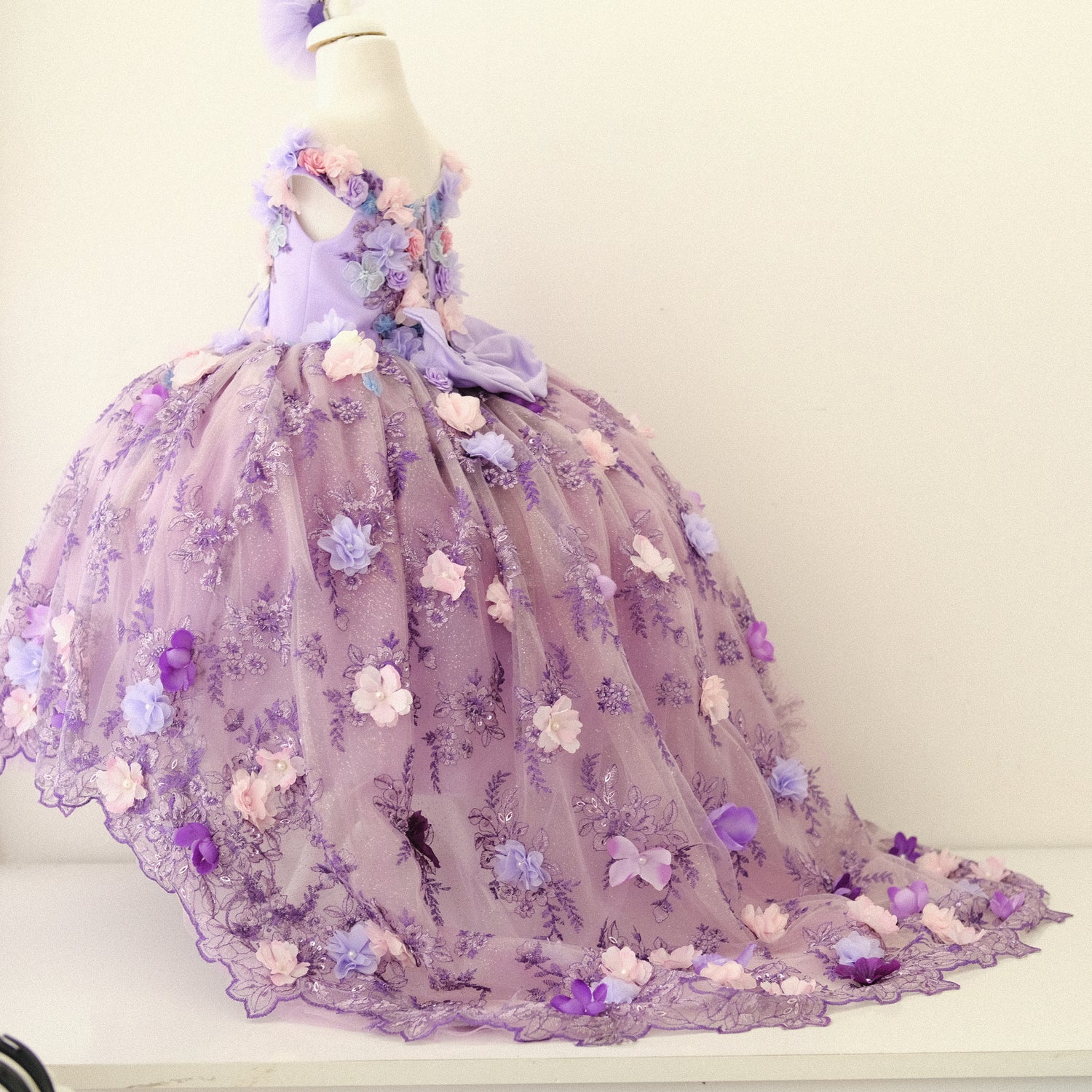 Beautiful lilac quinceañera dress with a satin bodice adorned with lace and 3D flowers, a voluminous tulle skirt with glittering accents, and a coordinating hair accessory, designed to create a magical look for any special occasion. Baby Girl Dress