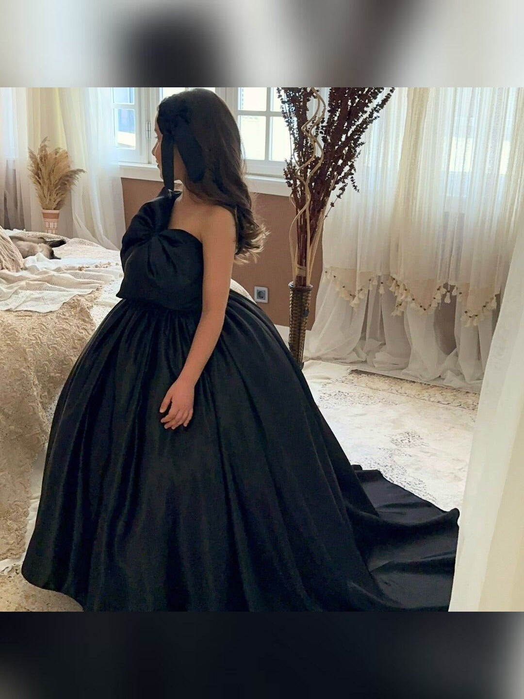 a woman in a black dress standing in front of a window