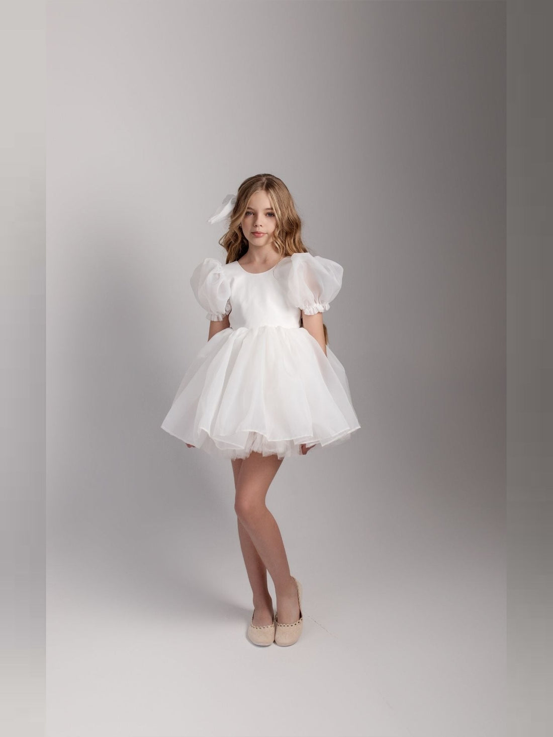 a little girl in a white dress posing for a picture