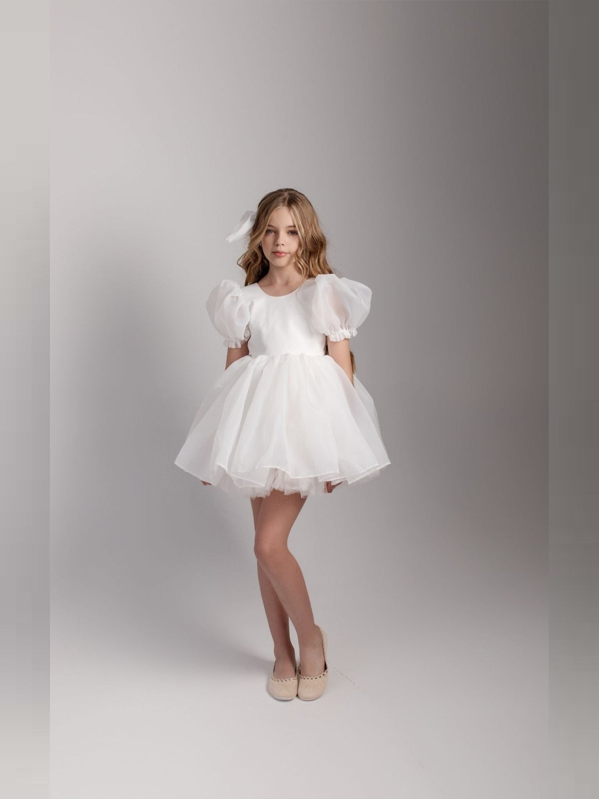 a little girl in a white dress posing for a picture