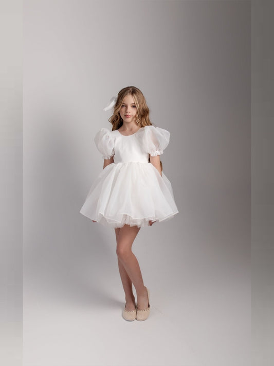 a little girl in a white dress posing for a picture