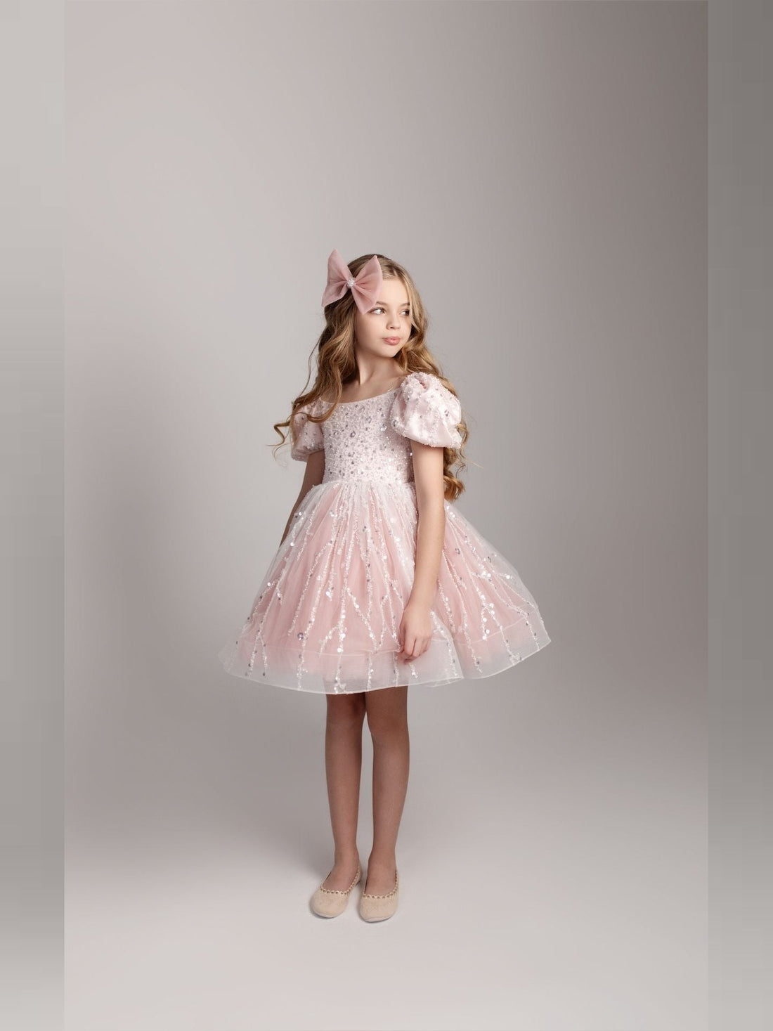 a little girl wearing a pink dress and a pink bow