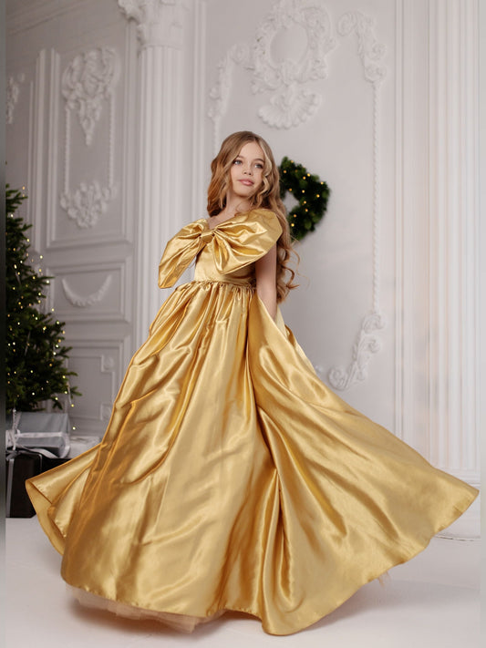 a woman in a gold dress standing in front of a christmas tree