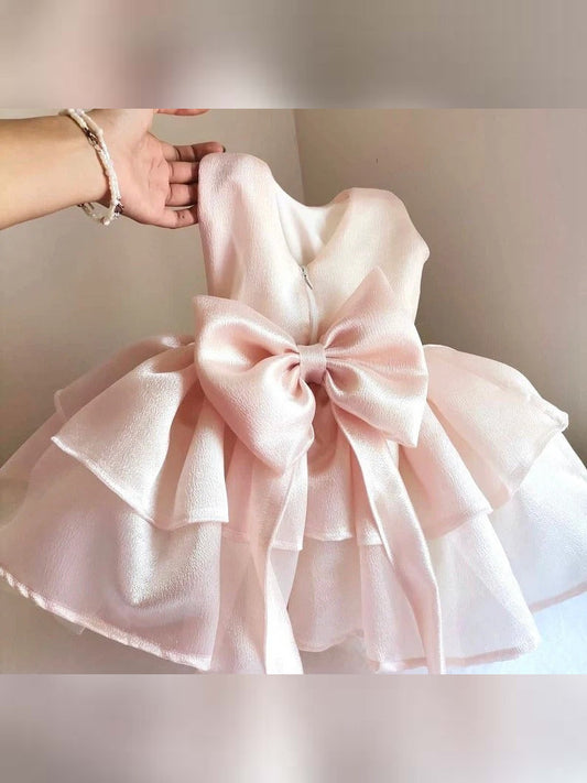 a hand holding a pink dress with a big bow