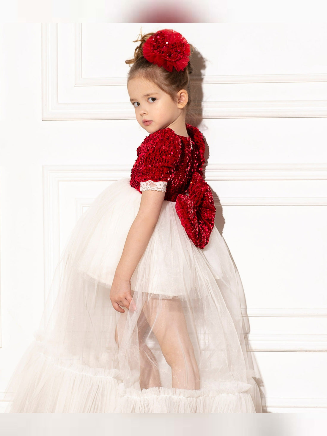 a little girl in a white dress with a red teddy bear