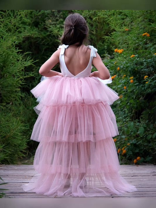 a little girl in a pink dress walking on a wooden walkway