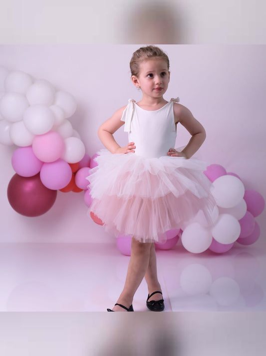 a little girl in a white dress standing in front of balloons