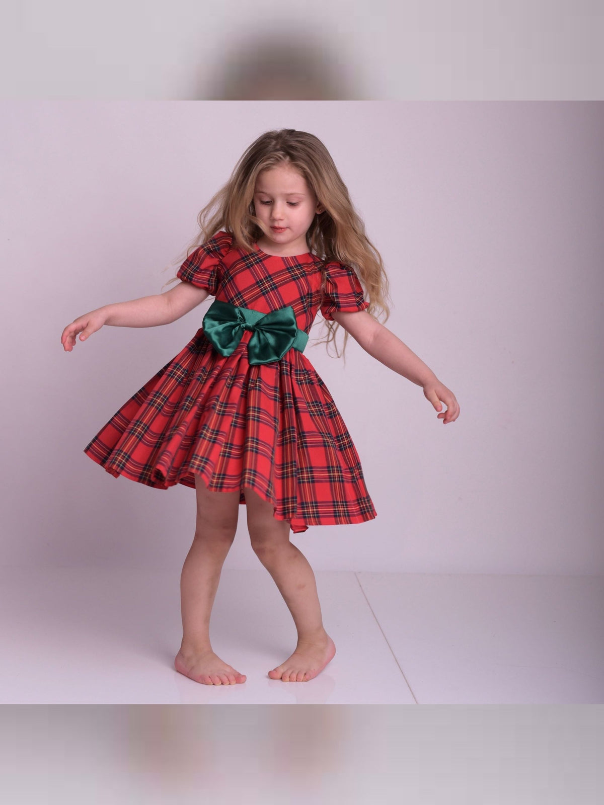 a little girl in a red and green dress