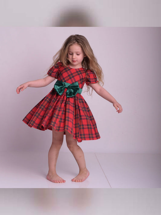 a little girl in a red and green dress