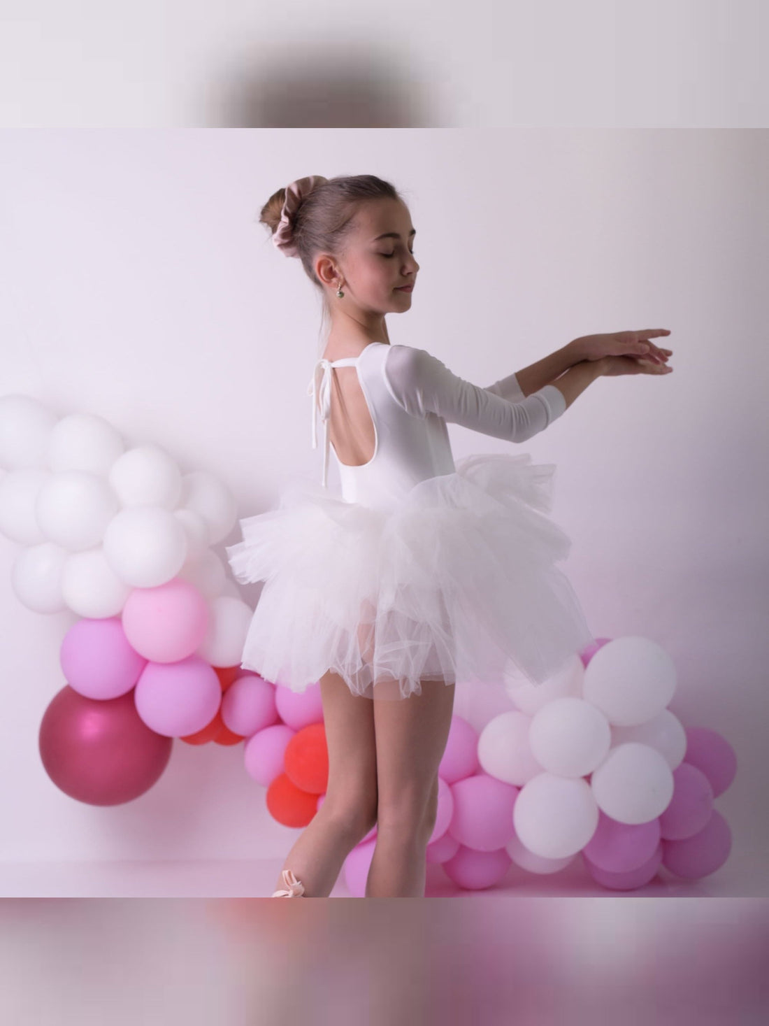 a young ballerina in a white tutu and ballet shoes