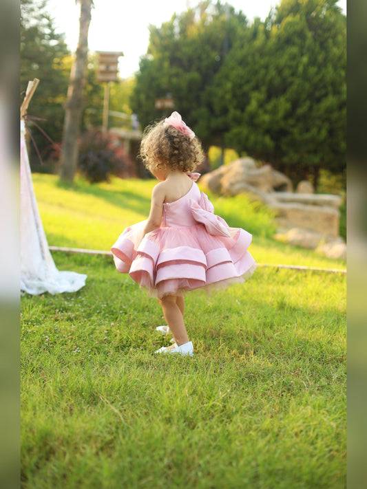 Blush pink one-shoulder dress for girls, showcasing a chic and modern design with a single strap and a flared skirt. Ideal for formal events, this dress adds a touch of sophistication and charm to any young girl's wardrobe.
