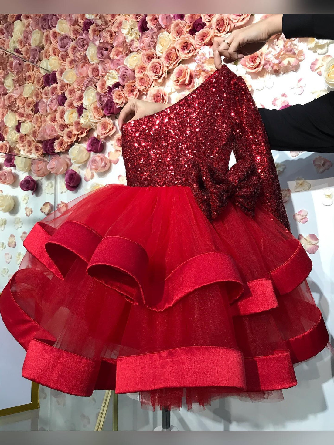  Back view of mini red baby girl Christmas dress with one shoulder and sparkling sequin details