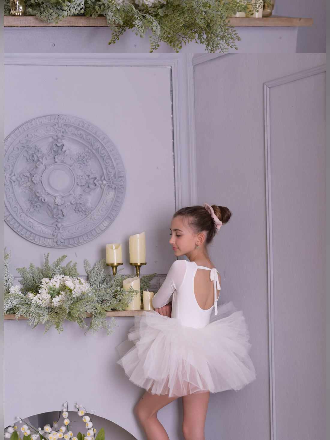 a little girl in a white dress standing on a shelf