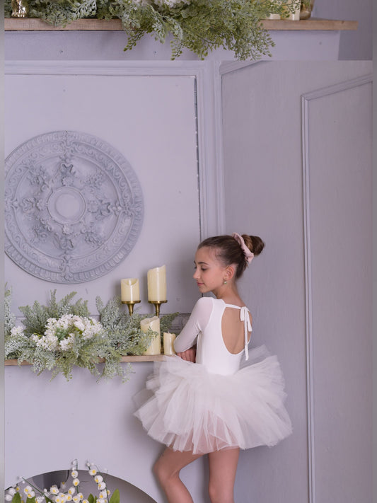 a little girl in a white dress standing on a shelf