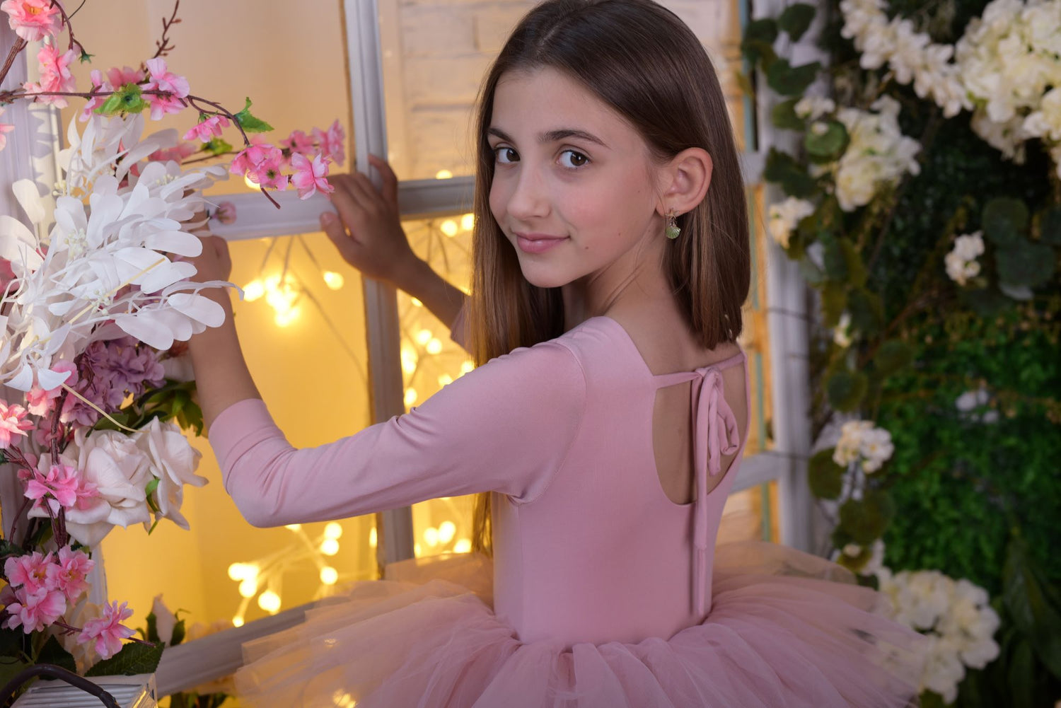 a little girl in a pink dress holding a bouquet of flowers