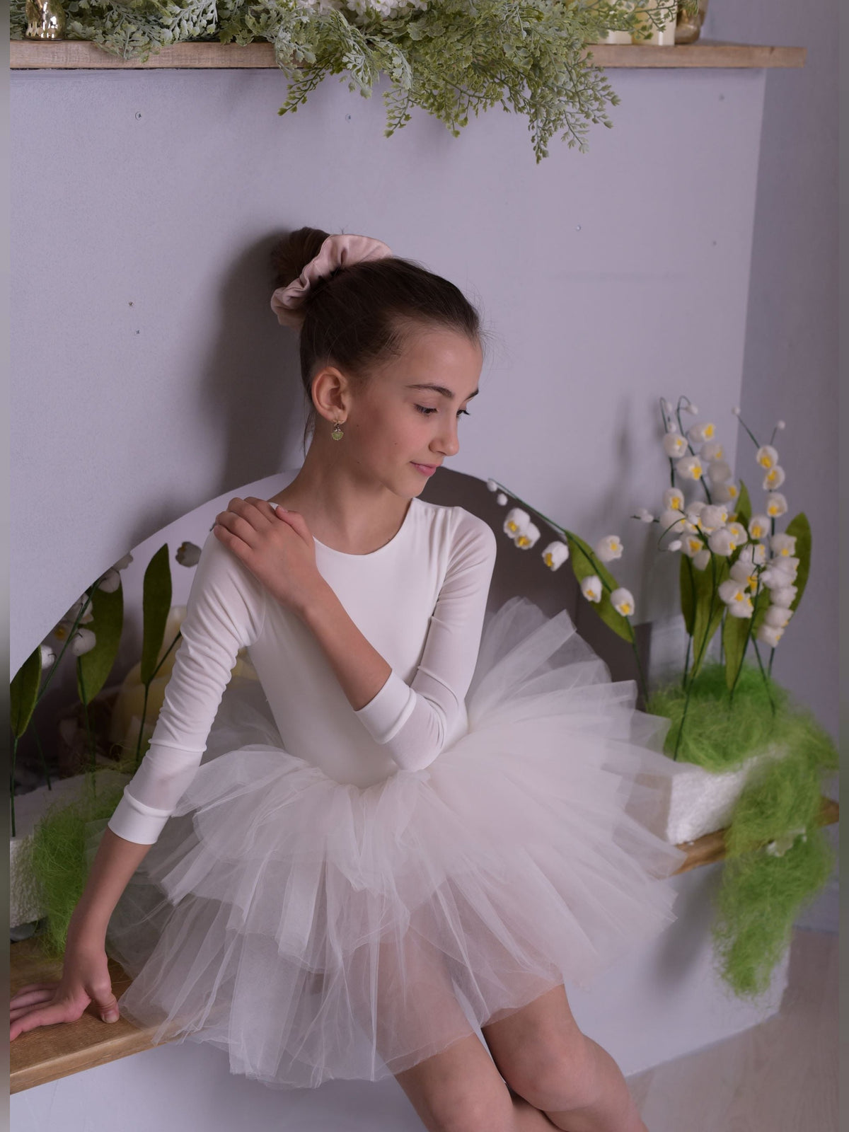 a young girl sitting on a chair wearing a tutu