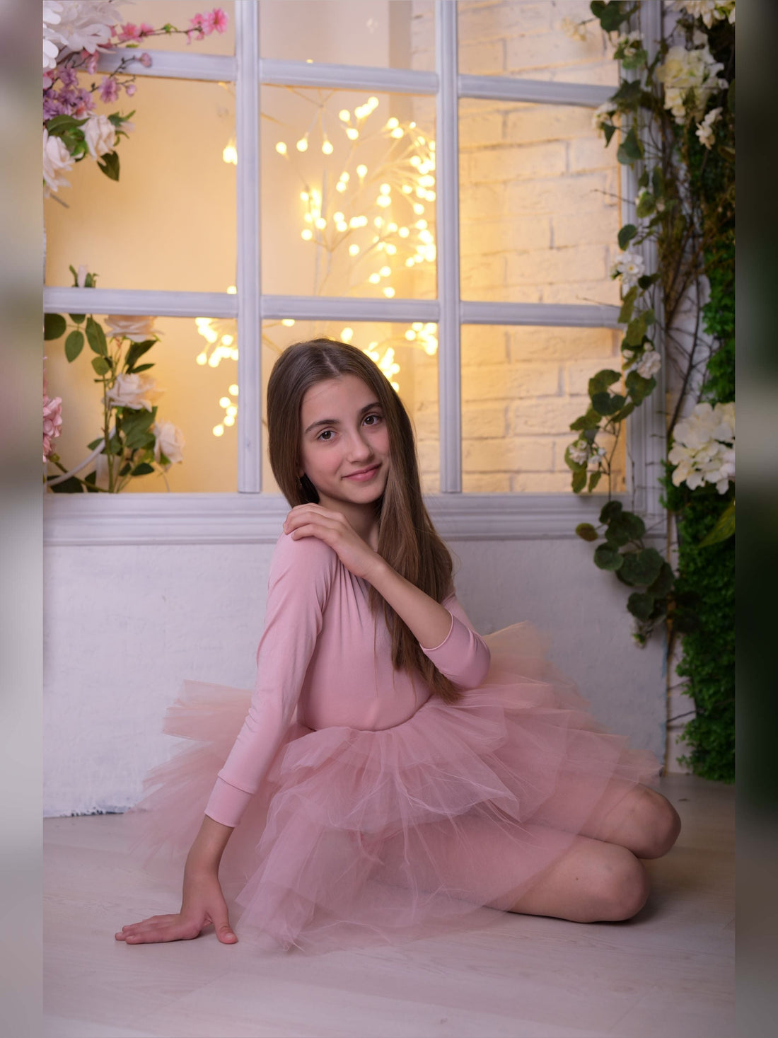 a girl in a pink dress sitting on the floor