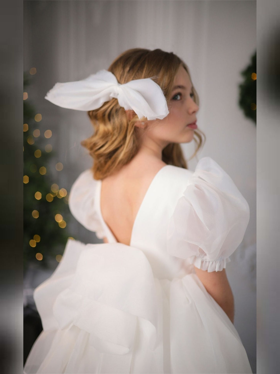 a woman in a white dress with a white bow in her hair