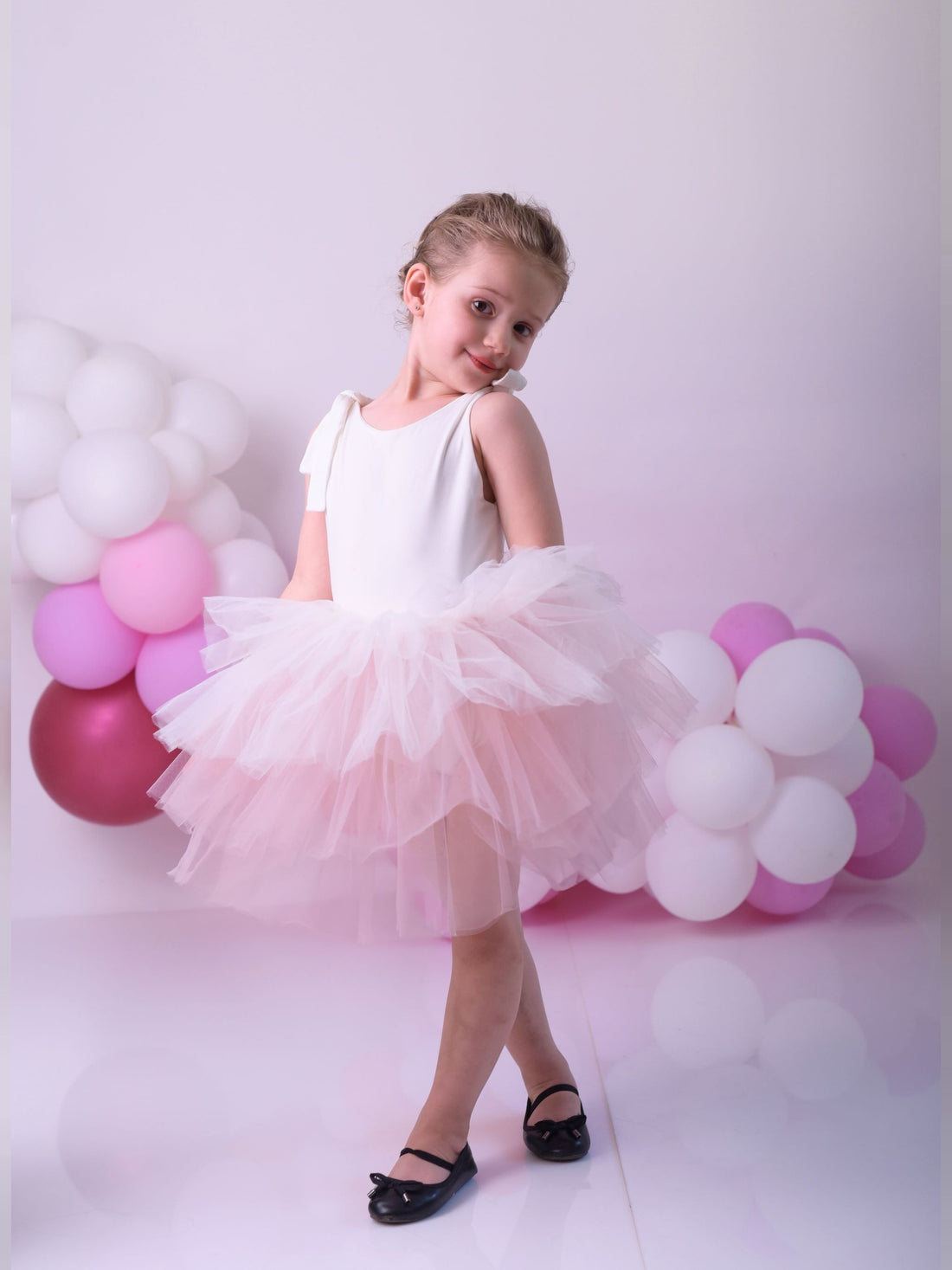 a little girl wearing a pink tutu and a white dress