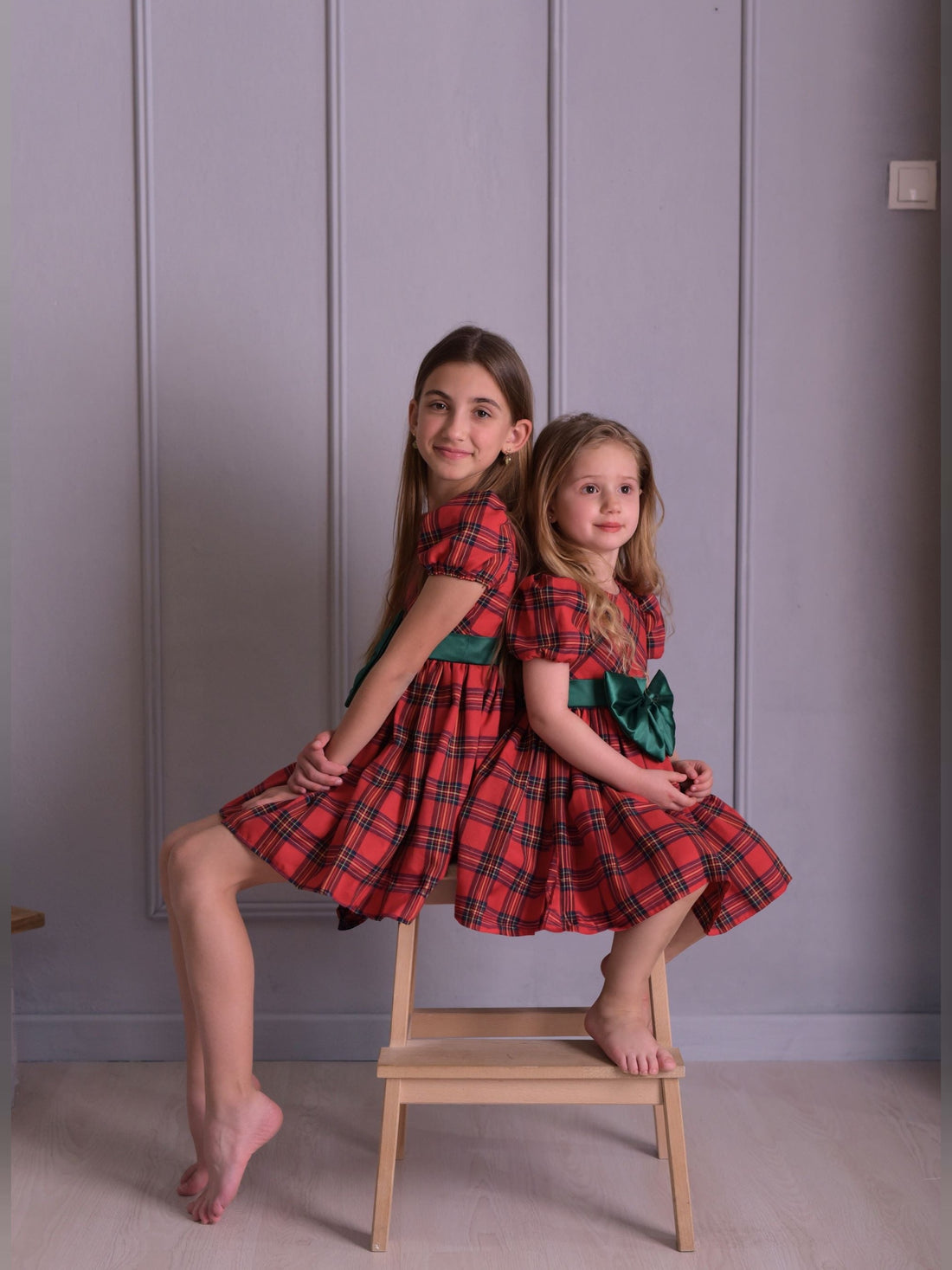 two little girls sitting on a chair posing for a picture