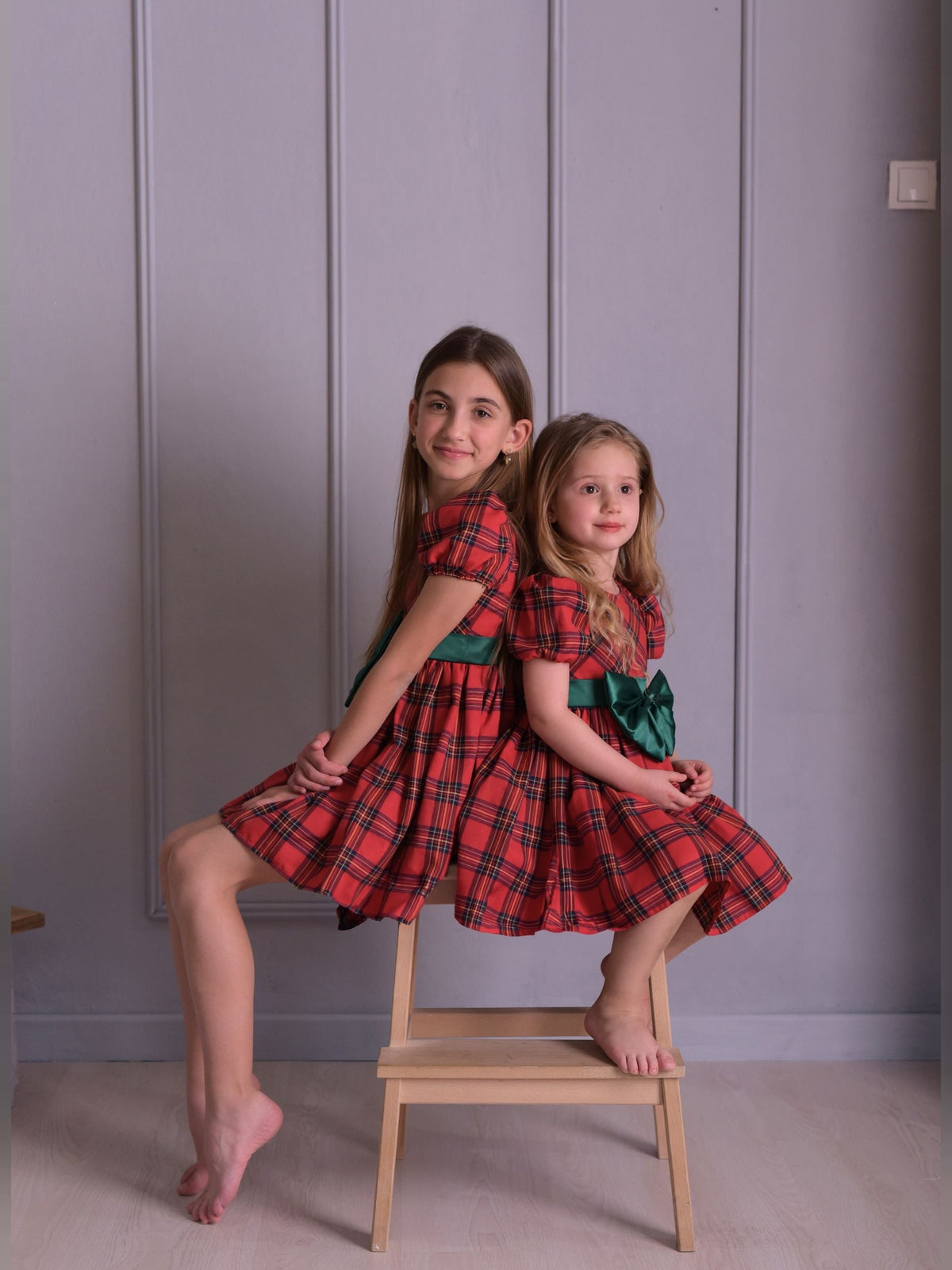 two little girls sitting on a chair posing for a picture