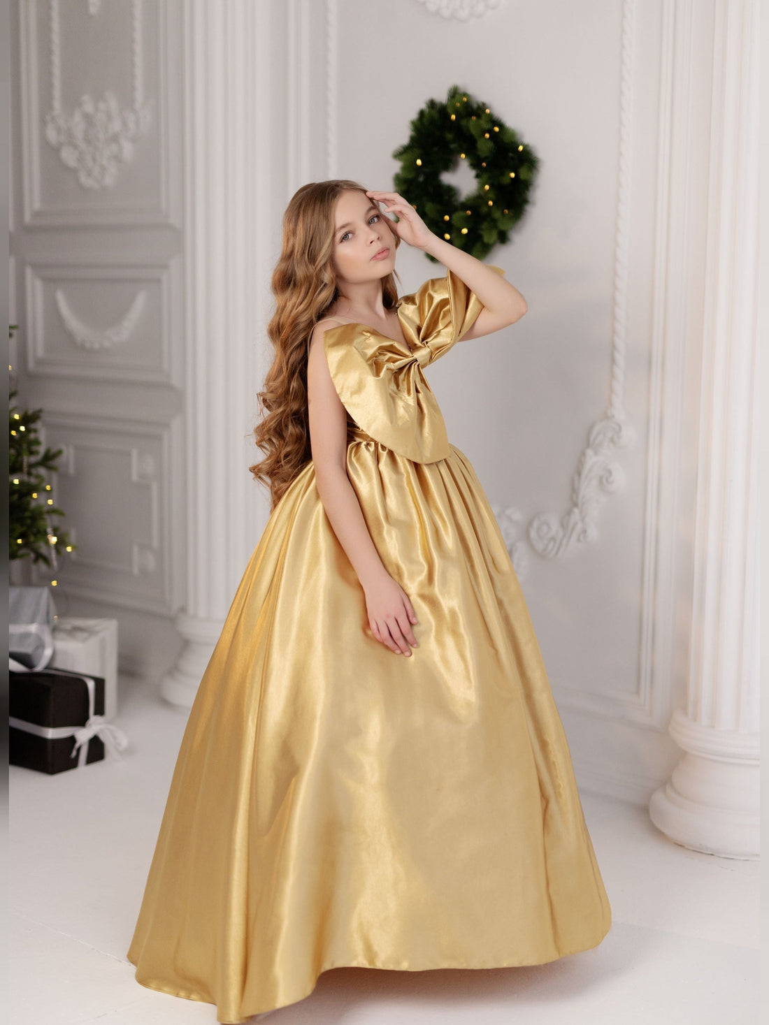 a young girl in a gold dress posing for a picture