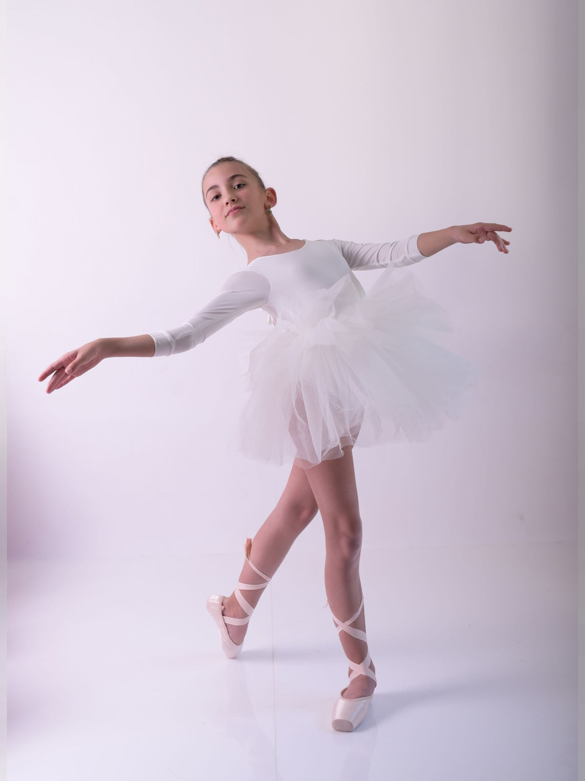 a young ballerina in a white tutu and ballet shoes