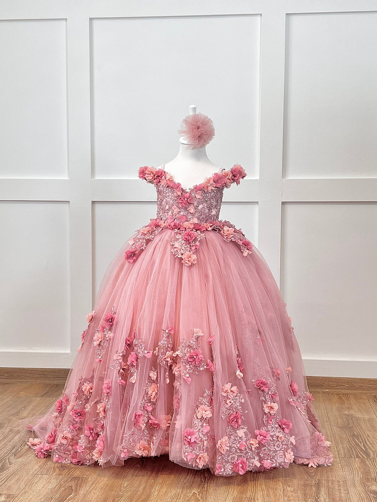 Quinceanera blush gown with satin bodice, lace, 3D colorful flowers, layered tulle skirt, and matching hair accessory.