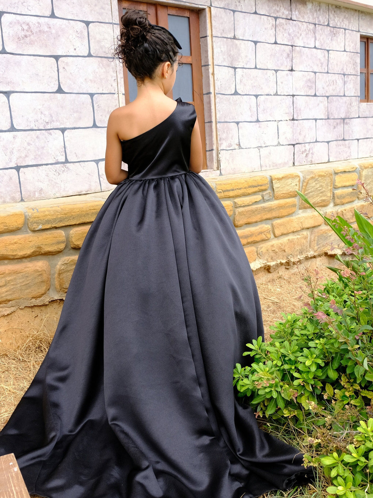 a woman in a black dress standing in front of a brick building
