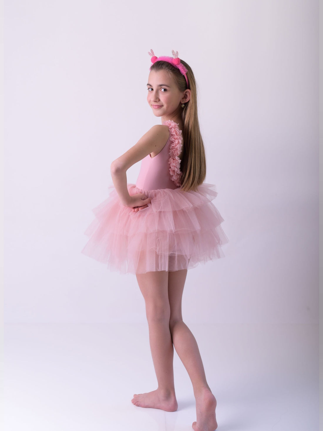 a little girl in a pink dress posing for a picture
