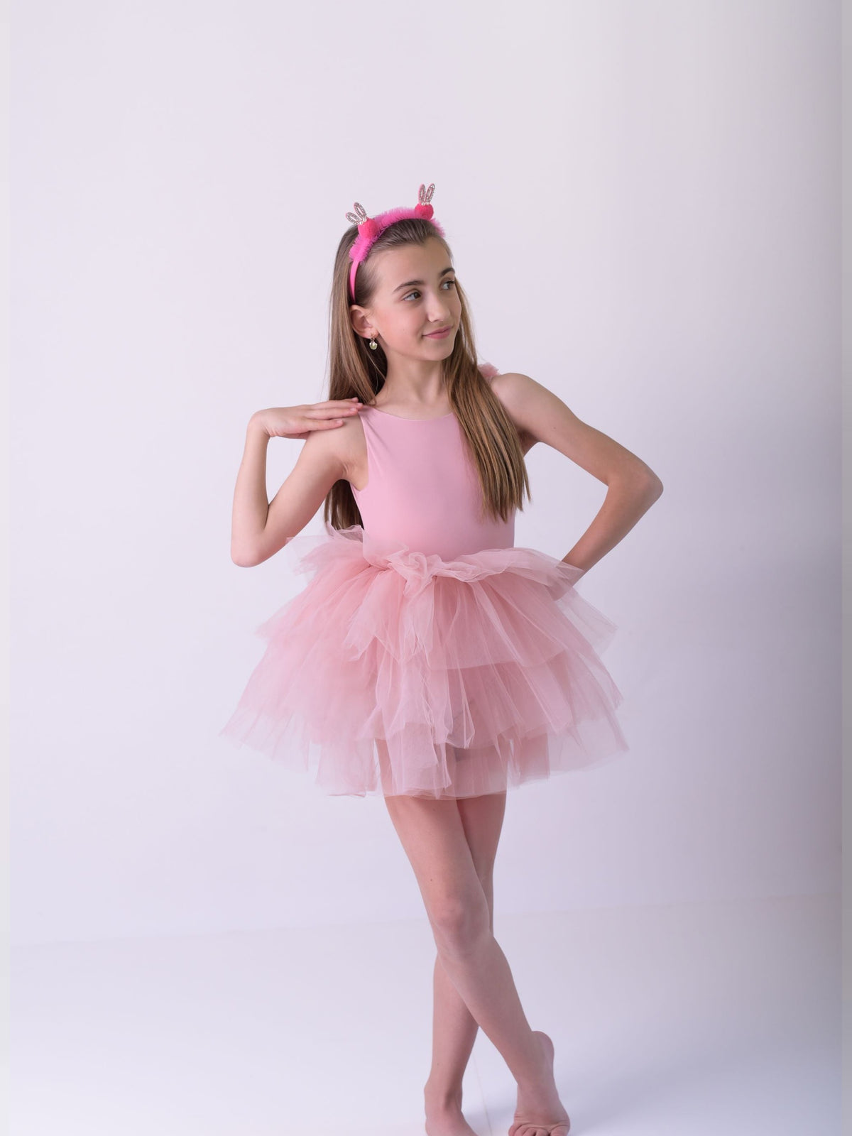 a little girl in a pink dress posing for a picture