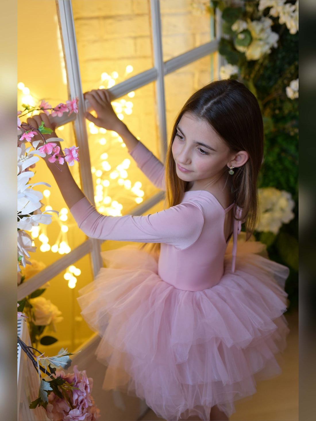 a little girl in a pink tutu holding flowers