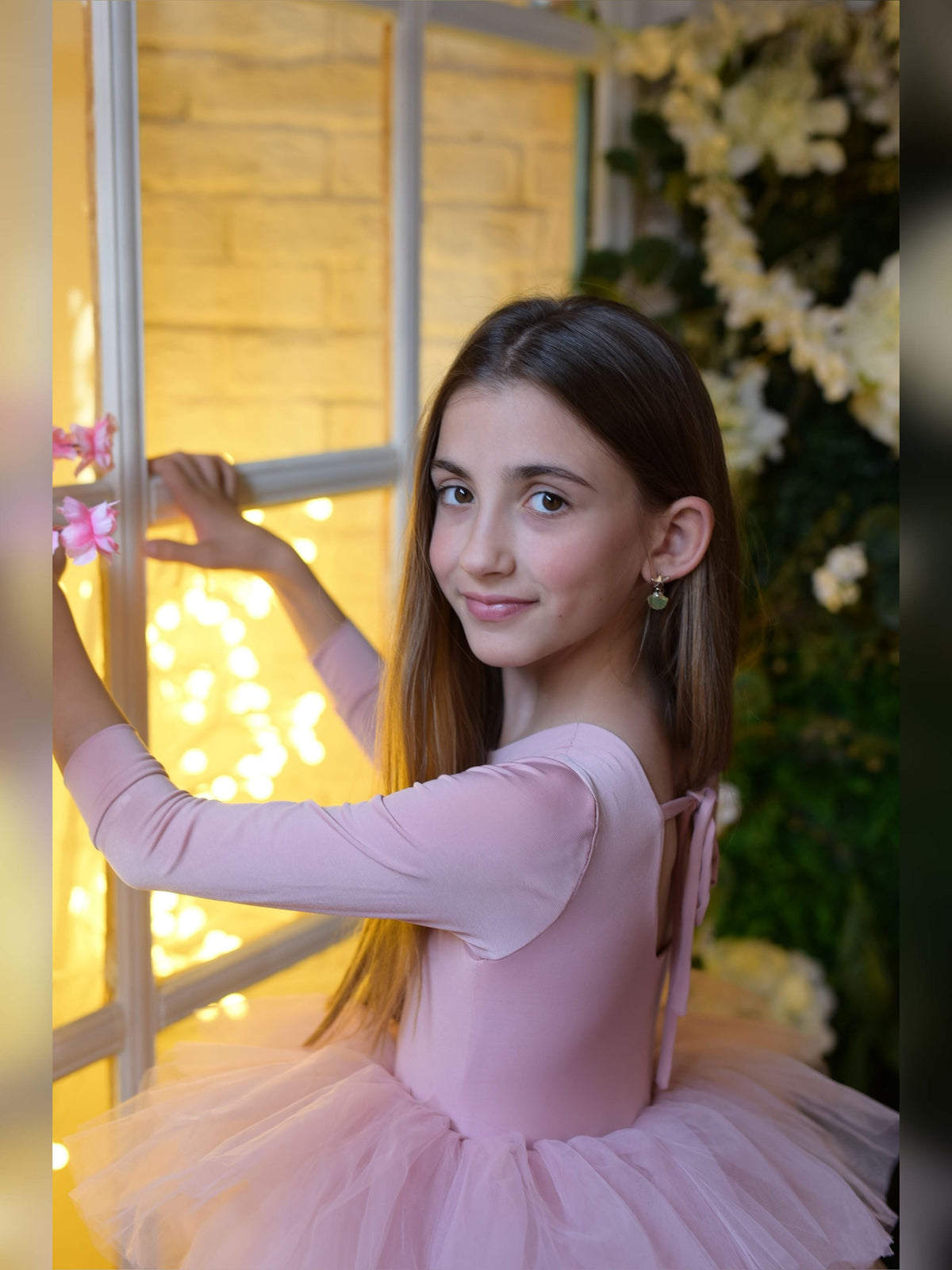 a young girl in a pink tutu holding a pink flower