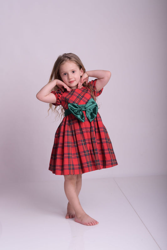 a little girl in a red dress posing for a picture