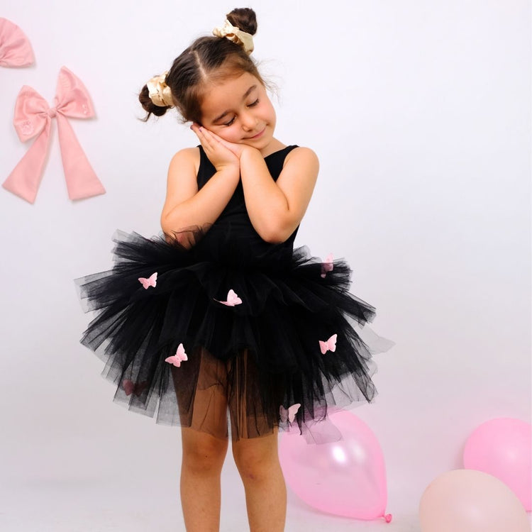 a little girl wearing a black tutu and a pink bow