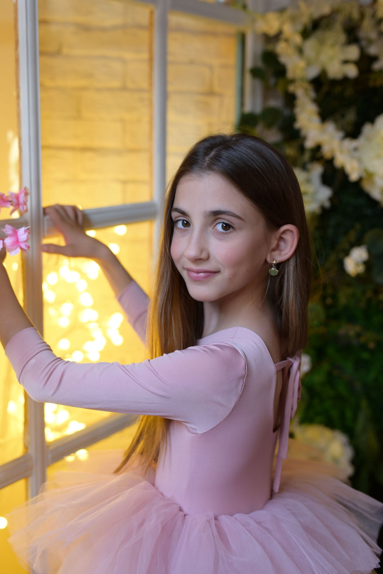 a young girl in a pink tutu holding a pink flower