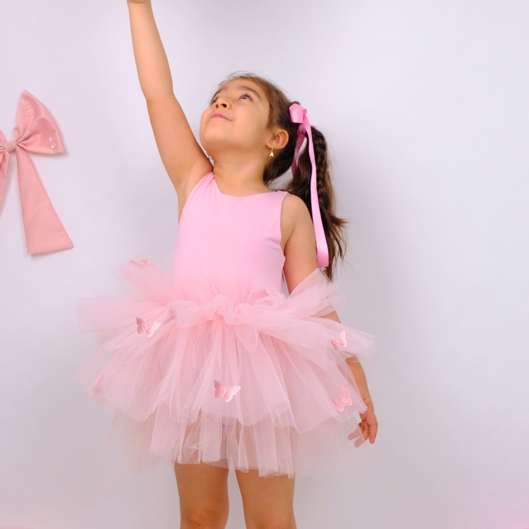 a little girl wearing a pink dress and a pink bow