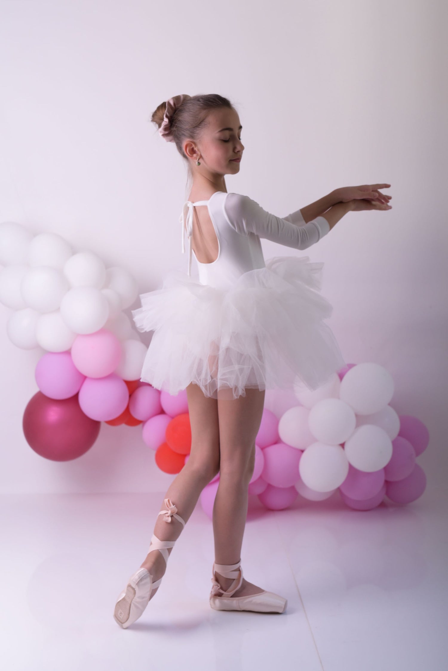 a young ballerina in a white tutu and ballet shoes