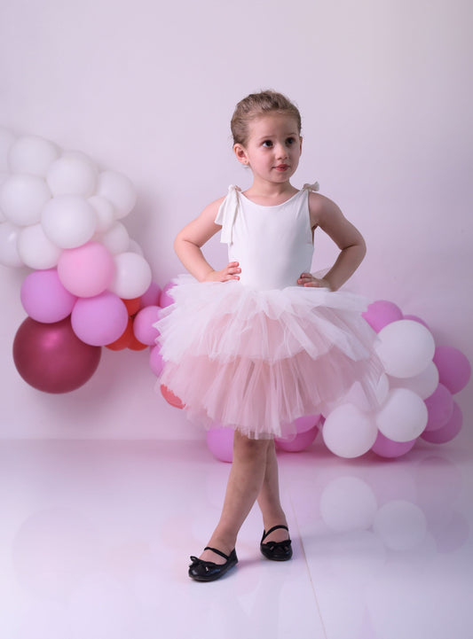 a little girl in a white dress standing in front of balloons