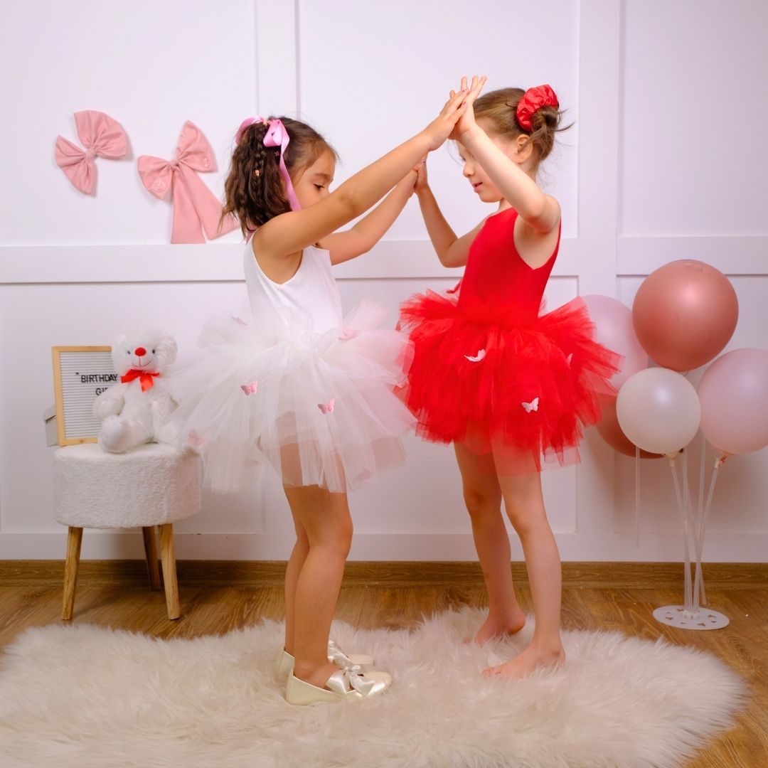 two little girls in red and white tutus playing with each other